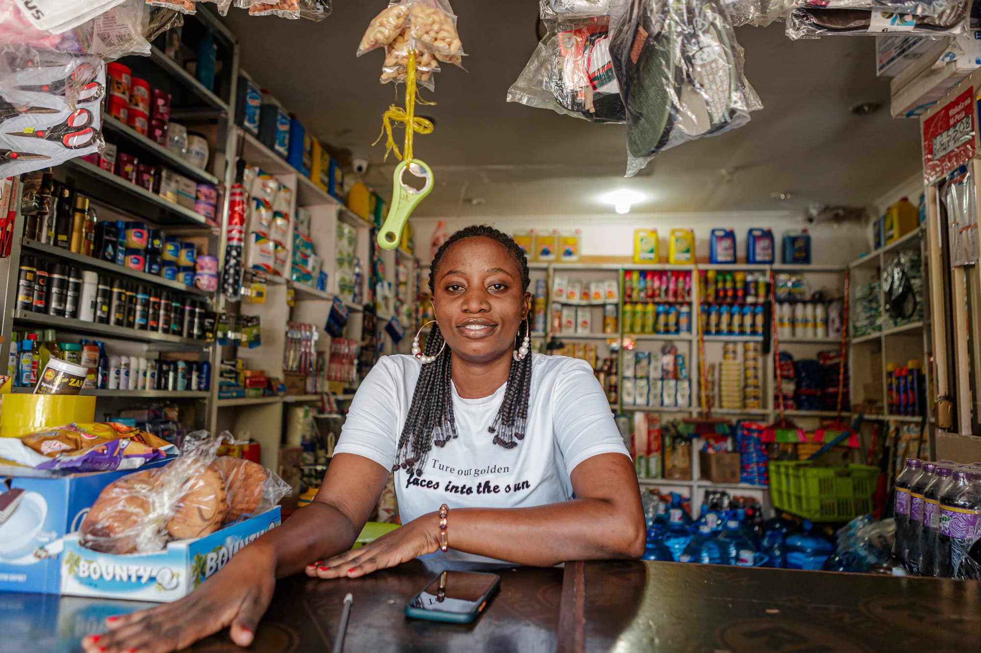 A shop owner smiling behind the counter of her well-stocked provisions store